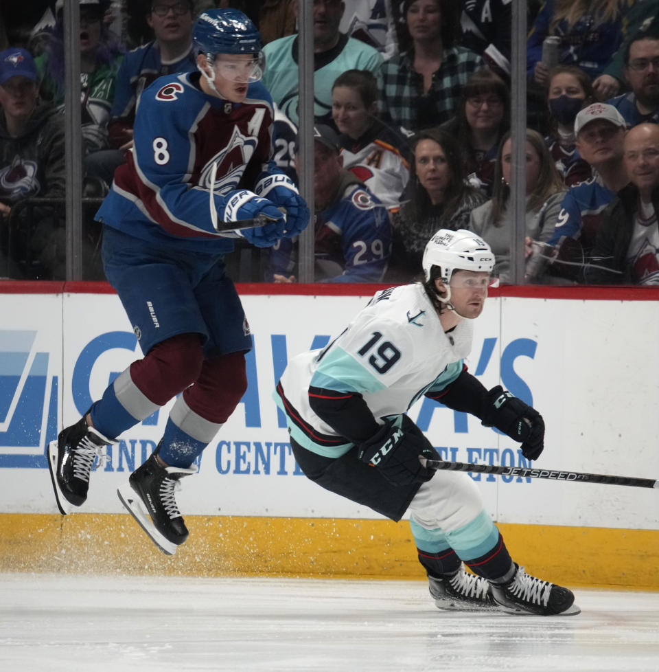 Colorado Avalanche defenseman Cale Makar, left, jumps to avoid a check by Seattle Kraken left wing Jared McCann (19) in the first period of an NHL hockey game Sunday, March 5, 2023, in Denver. (AP Photo/David Zalubowski)