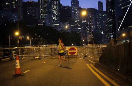 A runner jogs along a street blocked by pro-democracy protesters near the government headquarters office in Hong Kong October 9, 2014. REUTERS/Carlos Barria