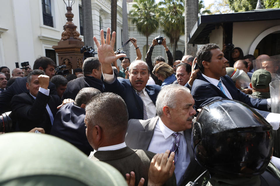 Opposition lawmakers push their way past National Guards on the grounds of the National Assembly, to enter the chamber for a session in Caracas, Venezuela, Tuesday, Jan. 7, 2020. Venezuelan opposition leader Juan Guaidó and lawmakers who back him pushed their way into the legislative building on Tuesday following an attempt by rival legislators to take control of the congress. Guaidó was sworn in on Tuesday. (AP Photo/Andrea Hernandez Briceño)