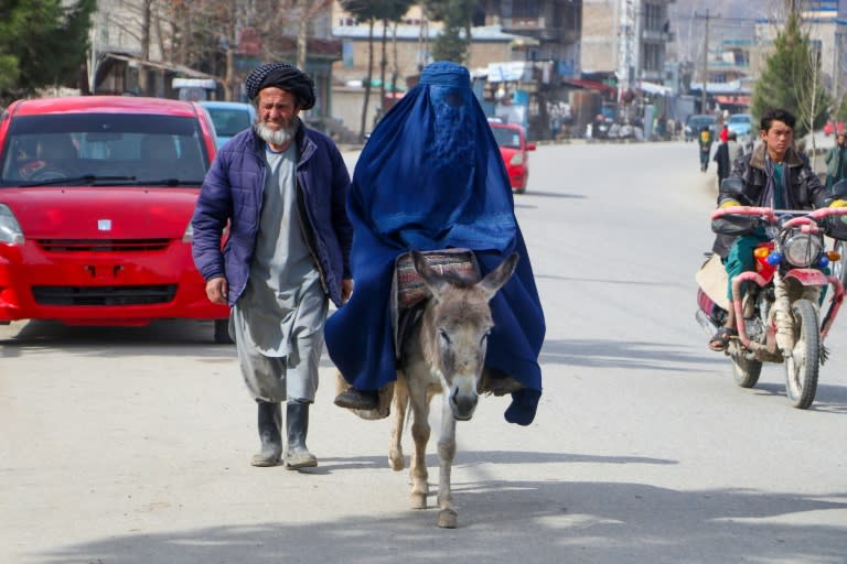 Une femme en burqa, se déplace à dos d'âne, accompagnée d'un homme à Fayzabad, le 14 mars 2024 en Afghanistan (OMER ABRAR)
