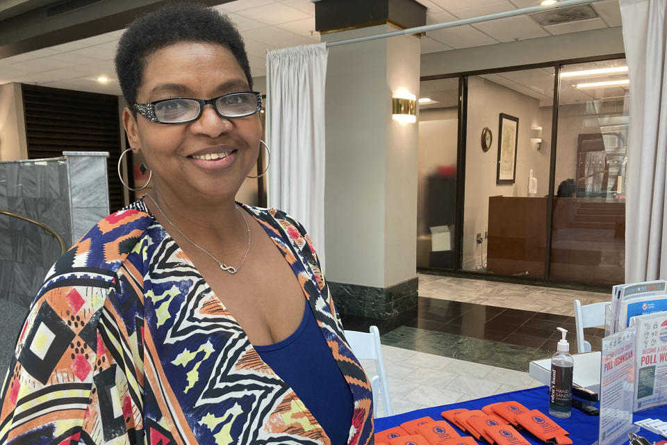 Amanda Rouser poses for a photo in front of a recruiting desk for new poll workers at Atlanta City Hall on Sept. 14, 2022, in Atlanta. Rouser was motivated to serve as a poll worker for the first time during the upcoming midterm election by false allegations of fraud against a Georgia poll worker after the 2020 presidential election. (AP Photo/Sudhin Thanawala)