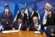 Israeli Prime Minister Naftali Bennett, back ceright, and Honduran President Juan Orlando Hernandez, speak as Israeli Foreign Minister Yair Lapid, front second right, and Honduran Foreign Minister Lisandro Rosales sign agreements between their two countries at the prime minister's office, in Jerusalem, Thursday, June 24, 2021. (Heidi Levine/Pool via AP).