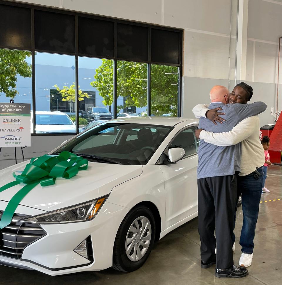 Isaac taylor (right) hugging Greg Heppler of Caliber Collision. Taylor previously biked 16 miles to work and in September 2023, he received a vehicle from the National Auto Body Council's Recycled Rides program.