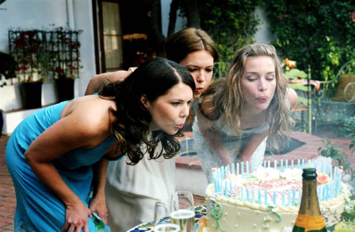 Lauren Graham, Mandy Moore and Piper Perabo lean over and blow out candles on a large birthday cake at an outdoor gathering in a scene from "Because I Said So"