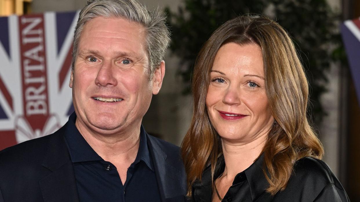 Keir Starmer in a black suit with his wife Victoria in a silk dress