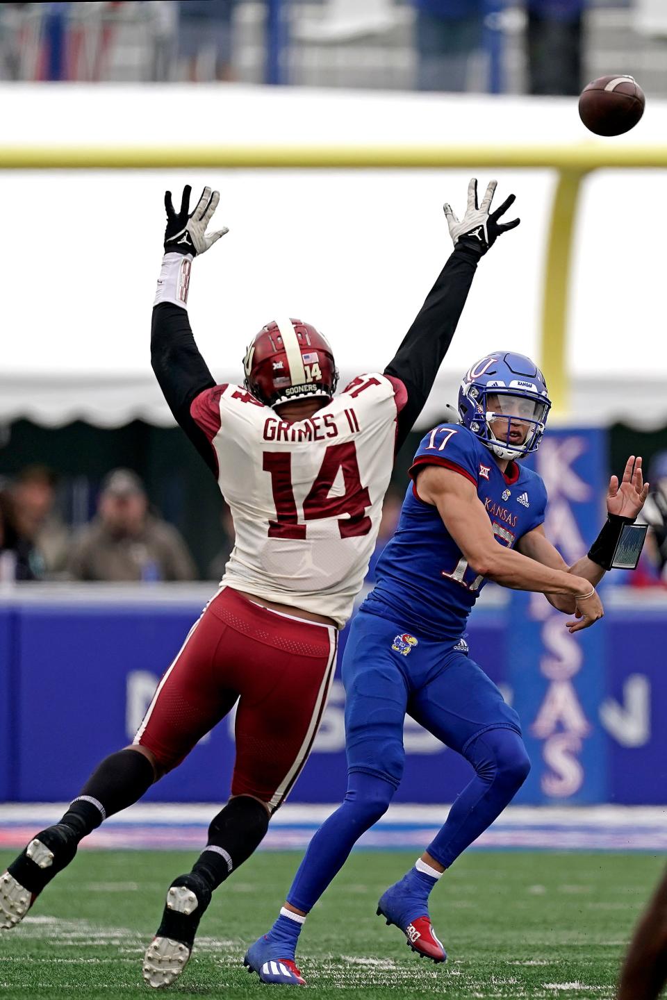 Kansas quarterback Jason Bean (17) throws under pressure from OU defensive end Reggie Grimes (14) during the second half.