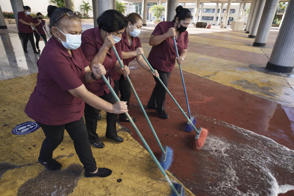 Workers clean the main entrance of Congress being occupied by supporters loyal to President-elect Xiomara Castro in Tegucigalpa, Honduras, Wednesday, Jan. 26, 2022. The new president's supporters say they want to block opposition attempts to take over leadership of Congress, which could threaten her ability to govern after she is sworn in Jan. 27. (AP Photo/Moises Castillo)