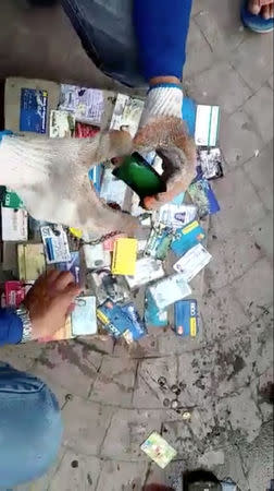 Sanitation workers sort out credit cards and IDs after retrieving wallets from a drain, after local media reported that a stash of wallets were clogging a canal in Poblacion, Batangas City, Philippines October 16, 2018, in this still image taken from a video obtained from social media. Domav Panganiban/via REUTERS