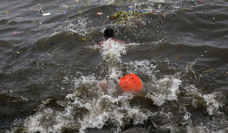 A man uses makeshift fins as he swims into the waters off the Manila Bay to collect recyclable materials, after Typhoon Sarika slammed central and northern Philippines, October 16, 2016. REUTERS/Erik De Castro