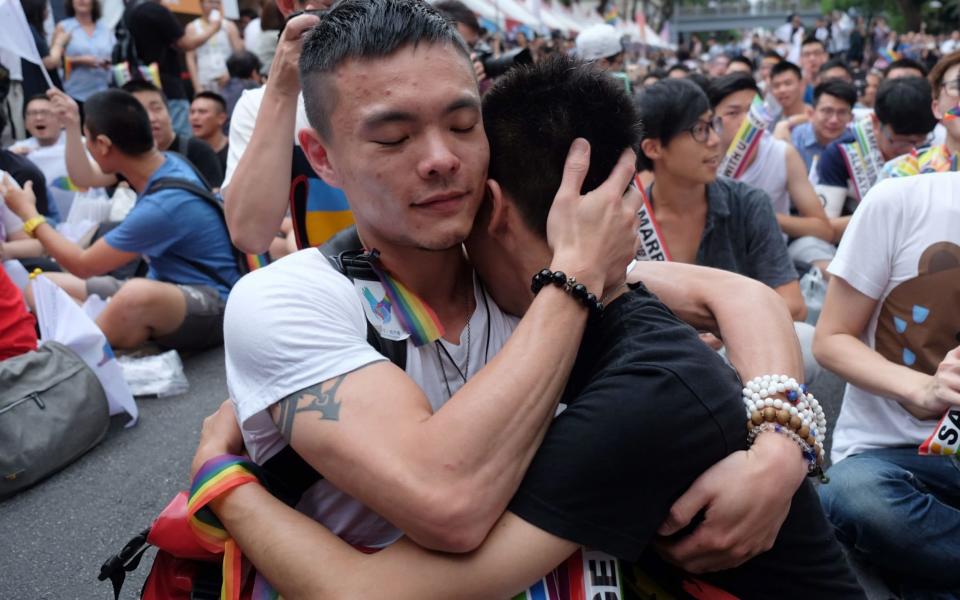 Same-sex activists hug outside the parliament in Taipei on May 24, after the landmark decision paving the way for the island to become the first place in Asia to legalise gay marriage - Credit:  SAM YEH/ AFP