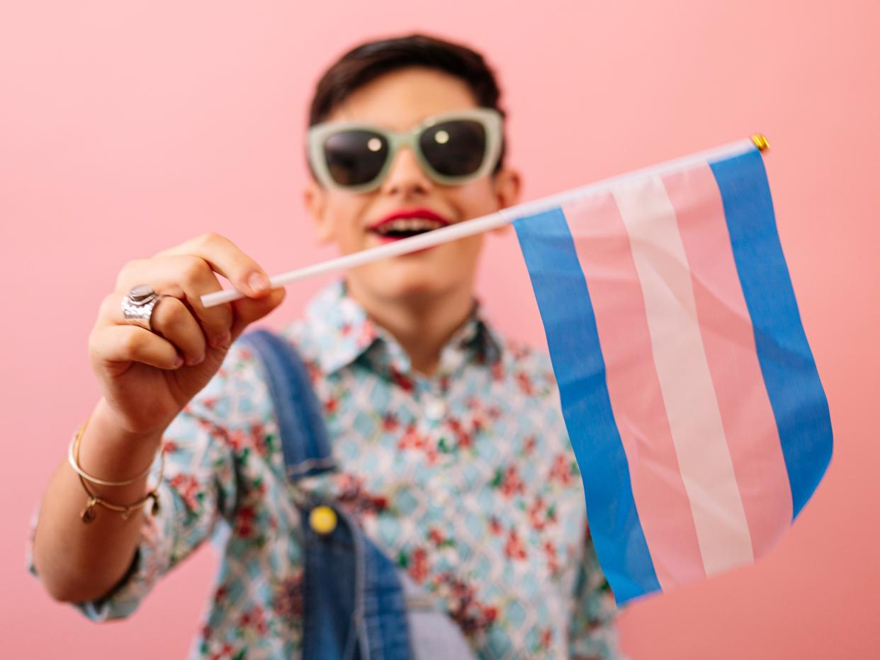 a young kid holding up a trans flag