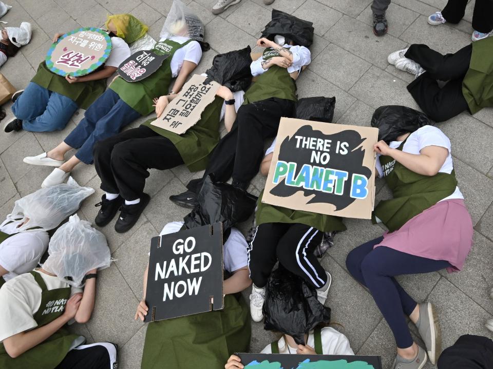 South Korean environmental activists lie on the ground with plastic waste during a campaign marking Earth Day against climate change (AFP via Getty Images)