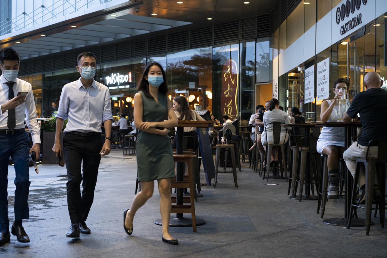 SINGAPORE, SINGAPORE - JULY 07: People wearing protective face masks walk past an alfresco area of a bar in Marina Bay Financial District on July 07, 2020 in Singapore. Residents will go to the polls to elect members of parliament on July 10. (Photo by Ore Huiying/Getty Images)