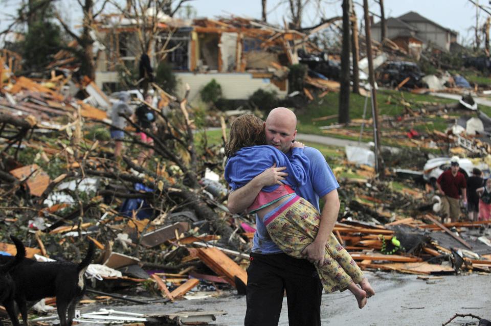 FILE - A man carries a young girl who was rescued after being trapped with her mother in their home after a tornado hit Joplin, Mo., May 22, 2011. A new study says warming will fuel more supercells or tornados in the United States and that those storms will move eastward from their current range. (AP Photo/Mike Gullett)