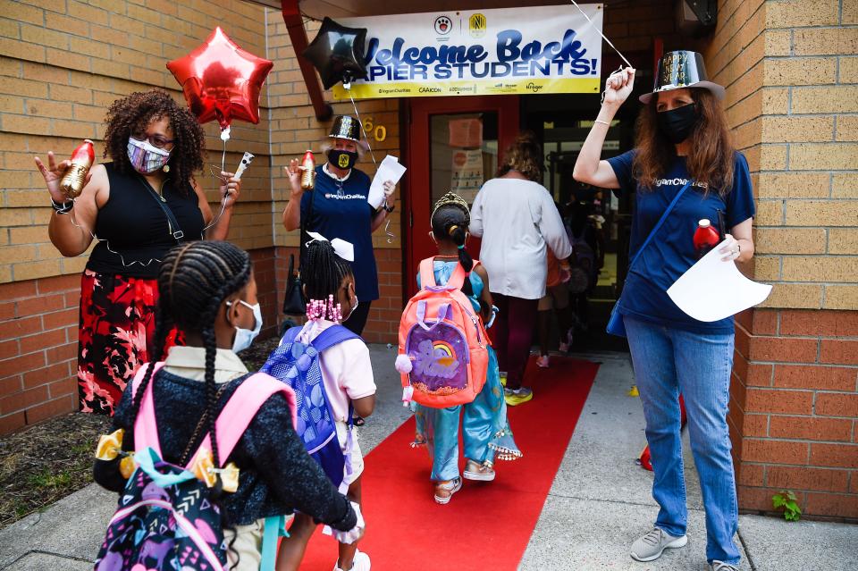 Teachers lead their students into Napier Elementary School on their first day of school by walking down the red carpet with the staff members cheering and waving at them in Nashville, Tenn., Tuesday, Aug. 10, 2021. 