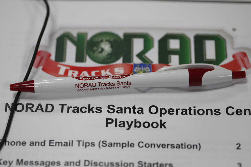 A pen rests on the playbook for volunteers who will be taking calls from around the globe in the NORAD Tracks Santa center at Petserson Air Force Base, Monday, Dec. 23, 2019, in Colorado Springs, Colo. (AP Photo/David Zalubowski)