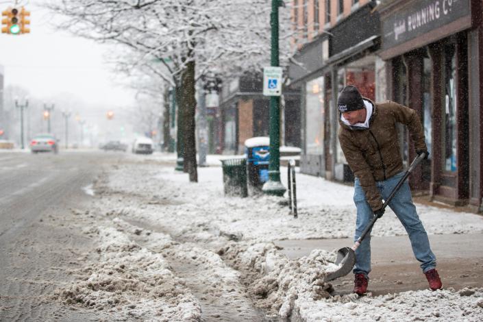 Nic Charnitsky, co-owner at Herbal Solutions shovels snow off the sidewalk in front of his business on Michigan Avenue in downtown Ypsilanti on Feb. 2, 2022.