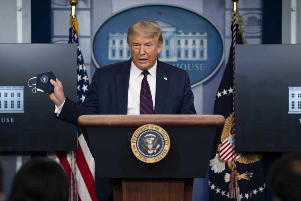 President Donald Trump holds a mask as he speaks during a news conference at the White House, Tuesday, July 21, 2020, in Washington. (AP Photo/Evan Vucci)