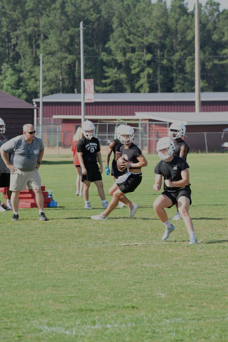 South Effingham High School quarterback Aubrey Heath takes the snap and looks for a receiver to clear on the new goal line play, while new assistant head coach Pat Collins talks to him about timing and movement.