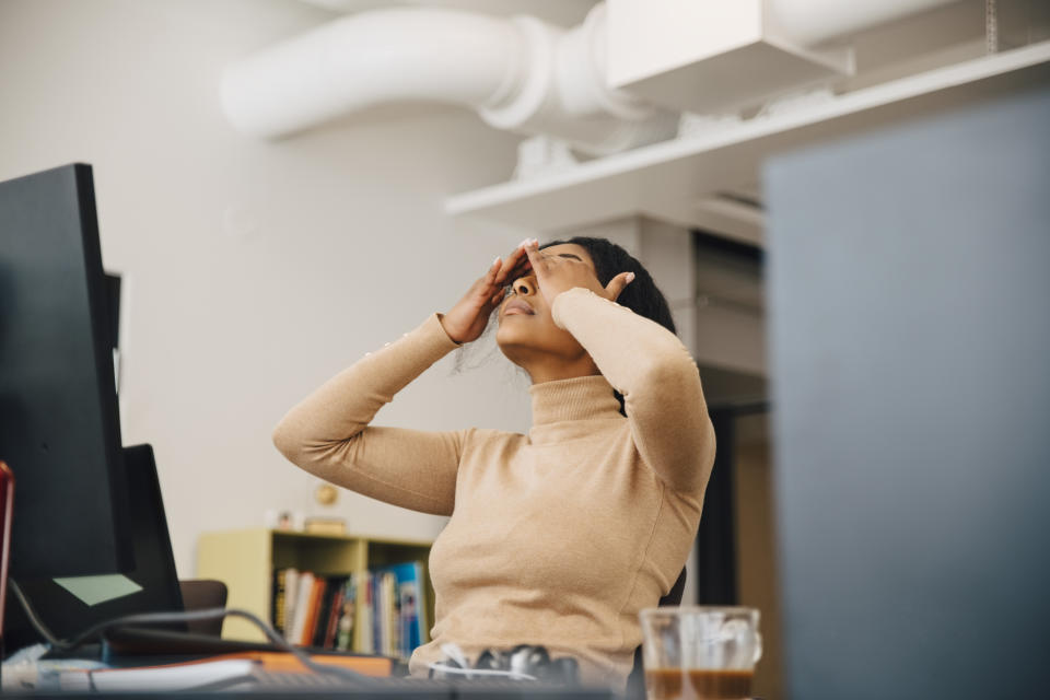 Frustrated female computer programmer with head in hands sitting in creative office