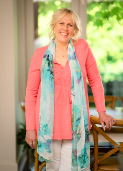 A blonde woman wearing a pink top and a blue scarf