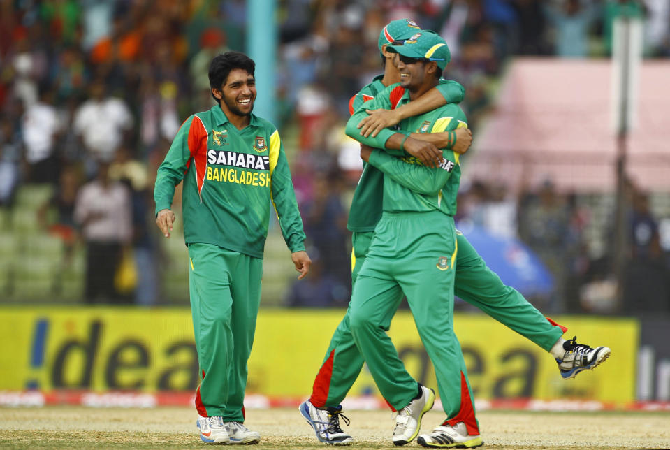 Bangladesh’s Moinul Haque, left, Naeem Islam, right, celebrate with an unidentified teammate the wicket of Afghanistan’s Nawroz Mangal during the Asia Cup one-day international cricket tournament between them in Fatullah, near Dhaka, Bangladesh, Saturday, March. 1, 2014. (AP Photo/A.M. Ahad)