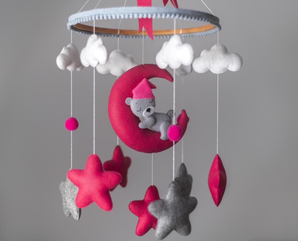 Baby mobile with felt stars, clouds, and a moon with a sleeping bear, used for nursery decoration