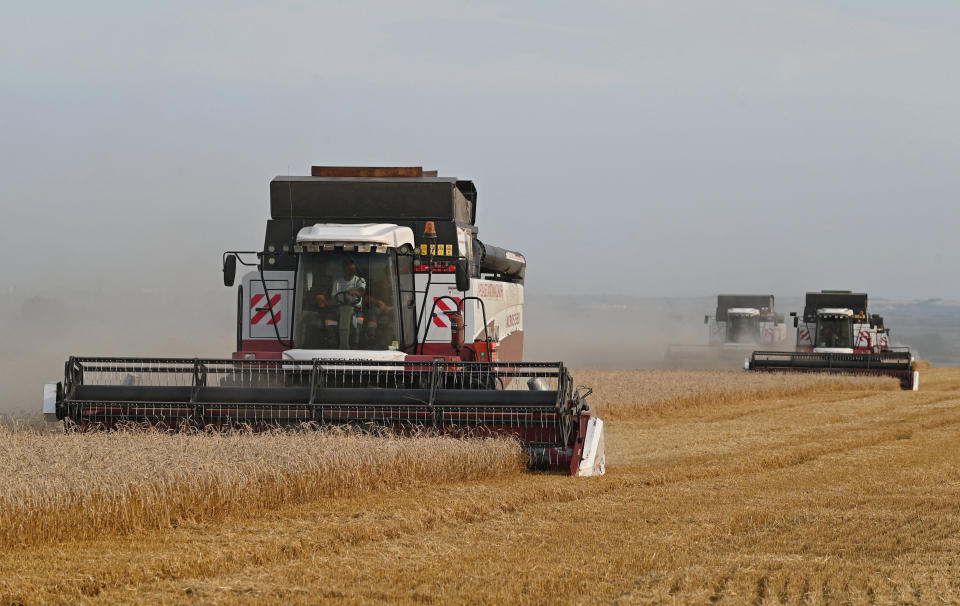 Three combine harvesters at work in a field.