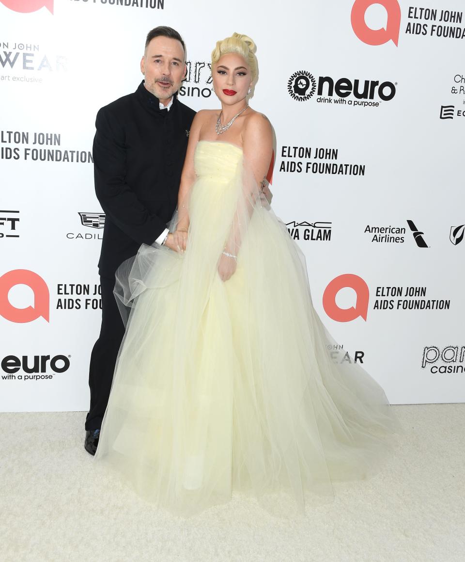 Gaga in a pastel yellow tulle strapless gown with a wide empire waist skirt. David is wearing an all black suit.