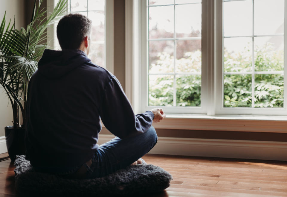 A man meditating on the floor.