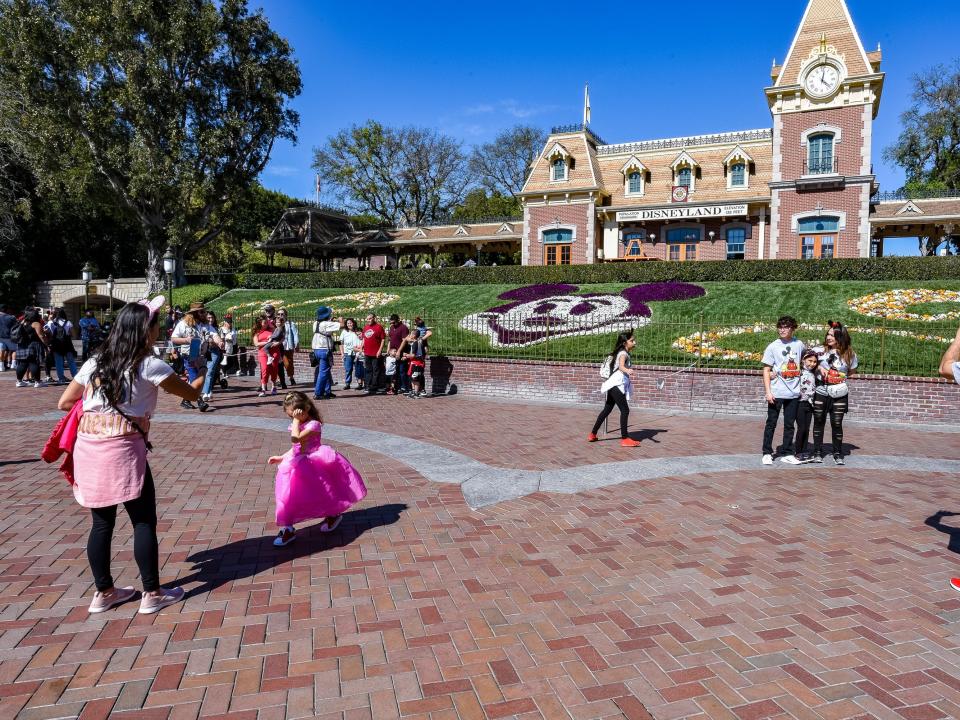 exterior shot of the entrance to disneyland with people milling around