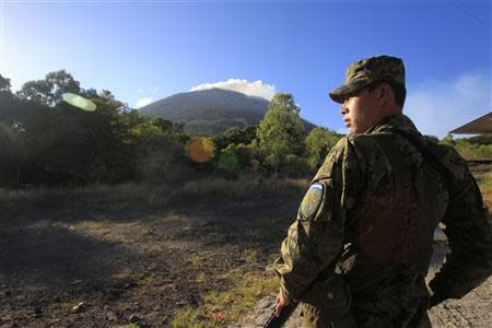 A soldier stands guard as the Chaparrastique volcano spews ash in the municipality of San Miguel December 30, 2013.REUTERS/Ulises Rodriguez