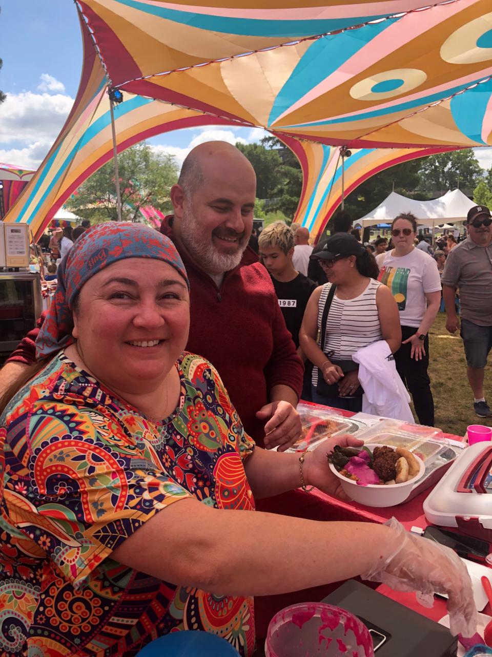 Tulin Sahin Babaoglu, left, of Mediterranean Michiana, serves up her cuisine with help from her husband,  Serhan Babaoglu, on Saturday, Sept. 9, 2023, at Fusion Fest at Howard Park in South Bend.