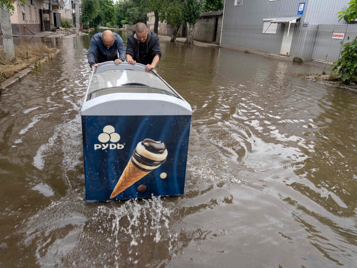 Residents push a freezer for ice-cream through the flooded area of Kherson (AFP via Getty Images)