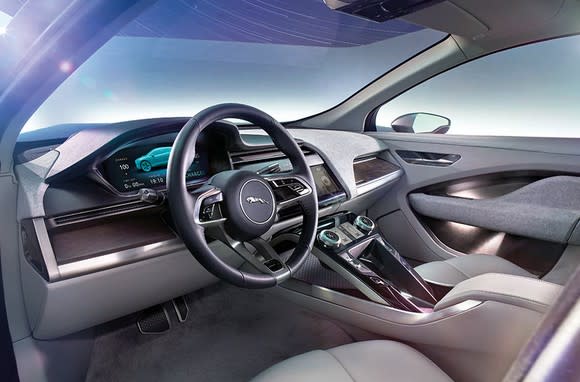 The interior of an I-PACE from the driver's side. Jaguar's leaping cat emblem is displayed on the wheel, and the displays are all electronic.