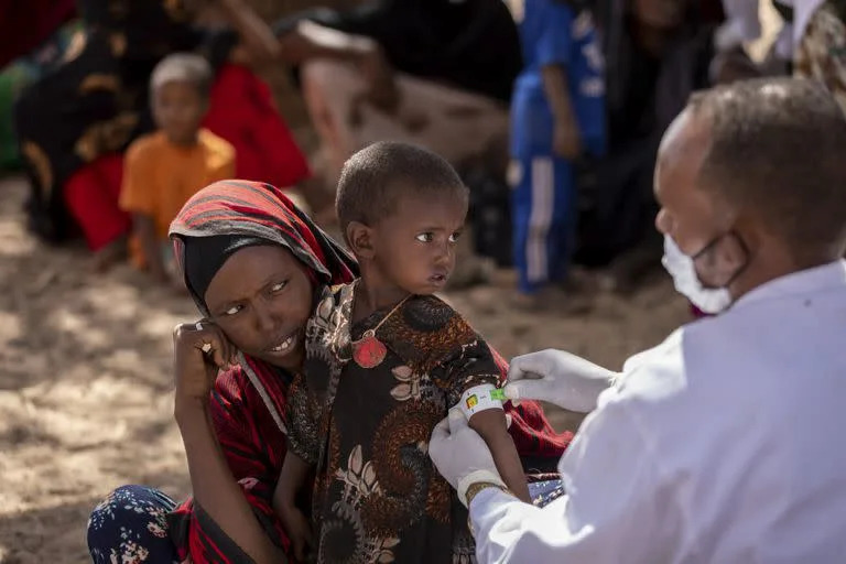 Un enfermero mide el brazo de Nimo Abdi, quien padece diarrea y vómitos y recibe tratamiento por desnutrición, mientras la sostiene su madre Shamis Dhire en una clínica móvil de UNICEF en la aldea de Barare, región somalí de Etiopía, 20 de enero de 2022. La sequía en el Cuerno de África amenaza millones de vidas. (Mulugeta Ayene/UNICEF via AP)