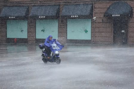 A man rides an electric scooter in the rainstorm as typhoon Lekima approaches in Shanghai