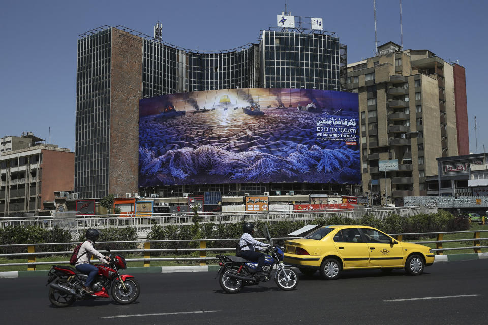 In this Wednesday, May 29, 2019 photo, People drive at Vali-e-Asr Square in downtown Tehran where an anti-Israeli billboard is place ahead of the Al-Quds, Jerusalem, Day, Iran. Mysterious attacks on oil tankers near the strategic Strait of Hormuz show how susceptible one of the world's crucial chokepoints for global energy supplies remains, 30 years after the U.S. Navy and Iran found themselves entangled a similarly shadowy conflict. The so-called "Tanker War" saw American naval ships escort reflagged Kuwaiti oil tankers through the Persian Gulf and the strait after Iranian mines damaged vessels in the region. It culminated in a one-day naval battle between Washington and Tehran, as well as saw America accidentally shoot down an Iranian passenger jet, killing 290 people. (AP Photo/Ebrahim Noroozi)