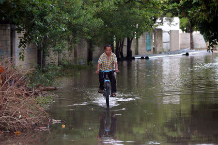 A man rides his bicycle through a flooded street after Tropical Storm Nate in Cancun, Mexico October 7, 2017. REUTERS/Henry Romero