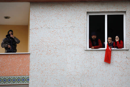 Supporters of Turkish President Tayyip Erdogan look out of a window near a special forces police officer during a rally for the upcoming local elections in Istanbul, Turkey, February 16, 2019. REUTERS/Umit Bektas