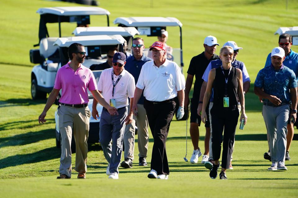 Donald Trump walks up to the fourth green with Donald Trump Jr, left, during the Pro-Am tournament Oct 27, 2022; before the LIV Golf series at Trump National Doral.