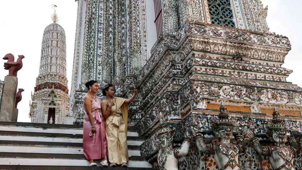 Tourists in Thai traditional dress take a selfie at Wat Arun on Vesak Day in Bangkok, Thailand on May 22, 2024. 