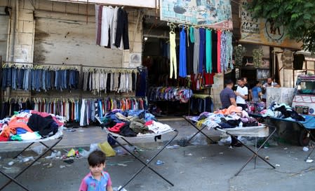 Clothing for sale is displayed along a street in the city of Idlib
