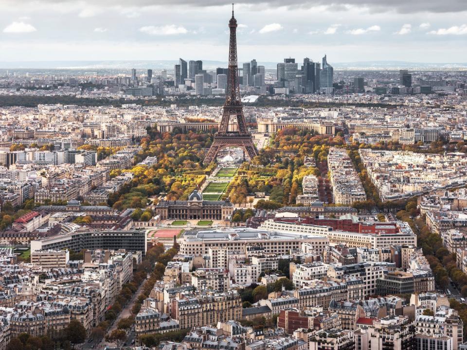 Aerial view of Paris, with several brown and gray buildings, and the Eiffel Tower standing above the city