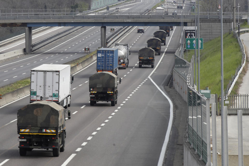 FILE - In this March 26, 2020 file photo, military trucks moving coffins of deceased people line up on the highway next to Ponte Oglio, near Bergamo, one of the areas worst hit by the coronavirus infection, on their way from Bergamo cemetery to a crematory in some other location as the local crematory exceeded its maximum capacity. Maddalena Ferrari lets herself cry when she finally takes off the surgical mask she wears even at home to protect her elderly parents from the coronavirus that surrounds her at work in one of Italy’s hardest-hit intensive care units. One day the tears were triggered by TV footage of coffins being hauled from her hometown of Bergamo by an army convoy. (AP Photo/Luca Bruno, File)