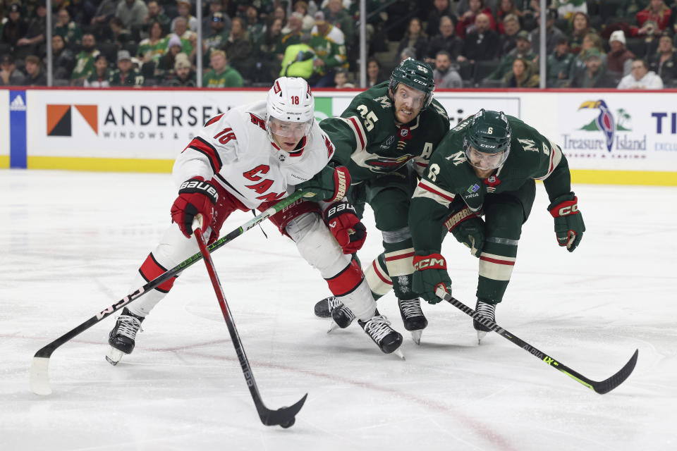 Carolina Hurricanes center Jack Drury (18) goes after the puck against Minnesota Wild defenseman Jonas Brodin (25) and defenseman Dakota Mermis (6) during the second period of an NHL hockey game Tuesday, Feb. 27, 2024, in St. Paul, Minn. (AP Photo/Stacy Bengs)