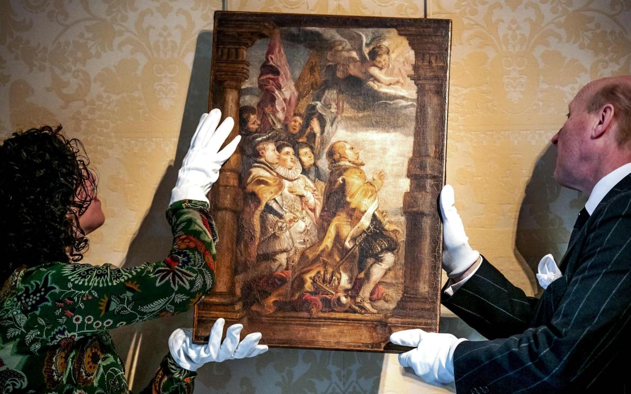 Art historian Emilie den Donkelaar (L) handles a newly discovered oil sketch named 'The secular hierarchy in worship' by Flemish painter Peter Paul Ruben - AFP