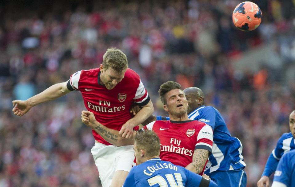 Arsenal's Per Mertesacker, left, tries to score against Wigan Athletic during their English FA Cup semifinal soccer match, at the Wembley Stadium in London, Saturday, April 12, 2014. (AP Photo/Bogdan Maran)