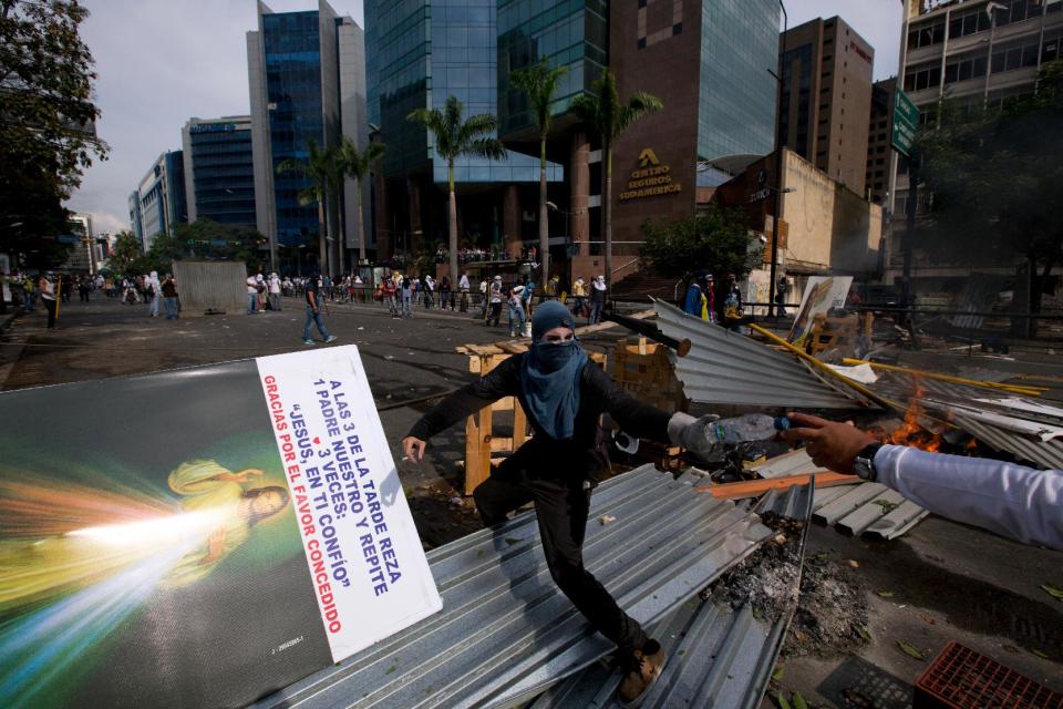 A masked anti-government demonstrator stands on a barricade during clashes with the Bolivarian National Police in Caracas, Venezuela, Tuesday, April 1, 2014. The barricades in Caracas’ middle-class neighborhoods and swaths of opposition-governed cities aim to disrupt, frustrate and ultimately trigger a popular revolt by Venezuelans fed up with a tottering economy, rampant crime and crackdown on dissent. But like the broader, mostly peaceful anti-government movement it grew out of, the tactic has so far failed to sow wider unrest. (AP Photo/Fernando Llano)