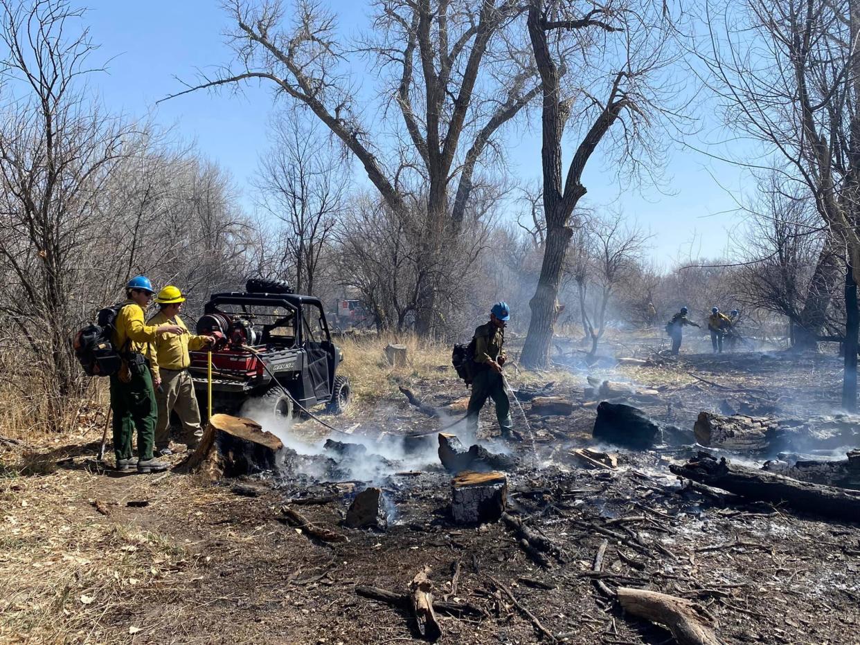 Members of the Pueblo Fire Department work to extinguish hot spots of a grassfire in April.